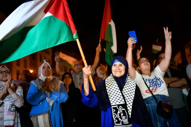 Otu nwaanyị na-amụ amụ ka o ji ọkọlọtọ mba Palestine ya na ndị ọzọ n'ihu ụlọomeiwu dị na Rabat, Morocco n'ụbọchị 17 Ọktoba 2023