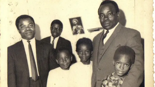 Ijeoma ve iki kardeşi babaları ve başka iki adamla birlikte. Sararmış siyah-beyaz bir fotoğraf.