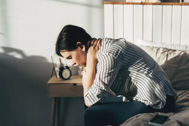 yatağında oturan depresyon geçiren bir kadın.
