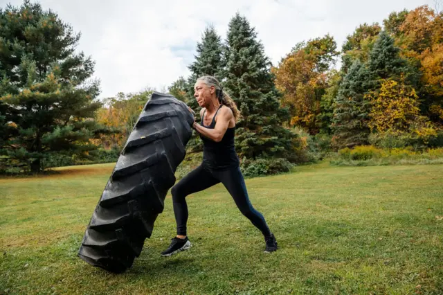 Una mujer entrena con una llanta gigante