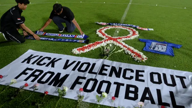 Suporter sepak bola meletakkan atribut Arema saat mengikuti doa bersama bagi korban Tragedi Kanjuruhan di Stadion Kapten I Wayan Dipta, Gianyar, Bali, Senin (3/10/2022).