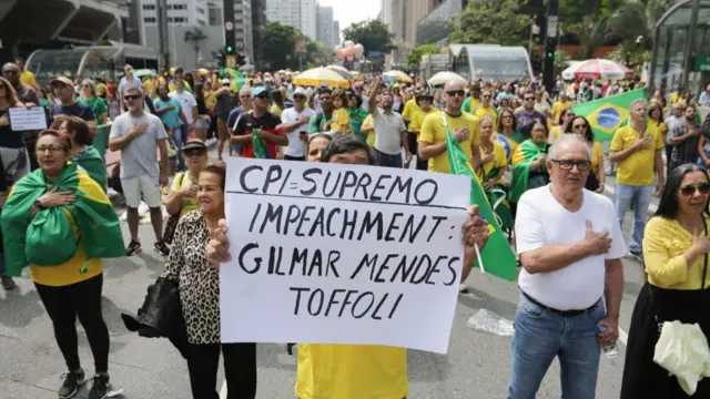 Manifestantes de verde e amarelo com um cartaz pedindo o impeachment dos ministros Gilmar Mendes e Dias Toffoli. 