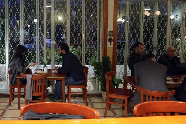 کافه‌ها از مکان‌هایی هستند که هنوز برخی از شهروندان برای دیدار یکدیگر و نگه داشتن روال عادی زندگی‌شان به آنجا می‌روند. در اینجا چند نفر در کافه ای در تهران نشسته اند