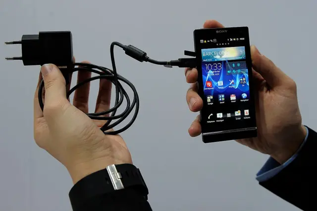 شخص يحمل شاحن هاتف محمول.