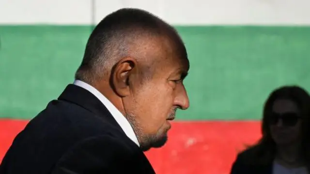 Глава ГЕРБ Бойко Борисов на фоне забора в цветах болгарского флага