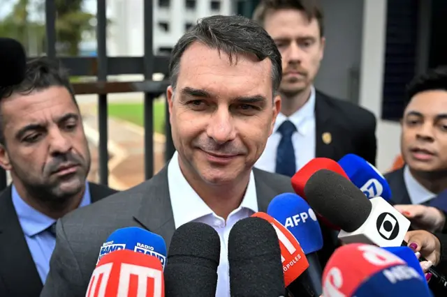 O senador Flávio Bolsonaro, filho do ex-presidente brasileiro Jair Bolsonaro, fala com jornalistas após deixar a sede da Polícia Federal, onde seu pai está detido, em Brasília, em 9 de dezembro de 2025