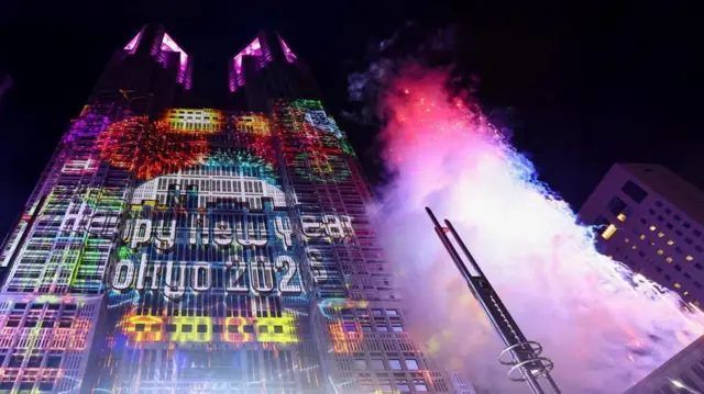 「Happy New Year Tokyo 2026」と映し出された東京都庁。右にはピンクや青の花火が上がり、白いスモークが上っている