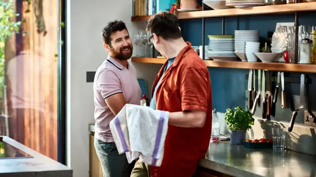 Casal na cozinha lavando e secando pratos