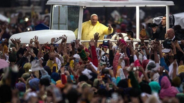 Giáo hoàng Francis mặc áo mưa màu vàng dưới cơn mưa như trút, vẫy tay chào đám đông ở Manila trong chuyến thăm Philippines