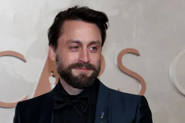Kieran Culkin sorrindo em frente a painel do Oscar