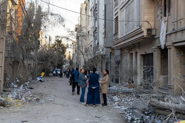 چند زن در میان خرابه‌های ناشی از حملات با هم صحبت می‌کنند.