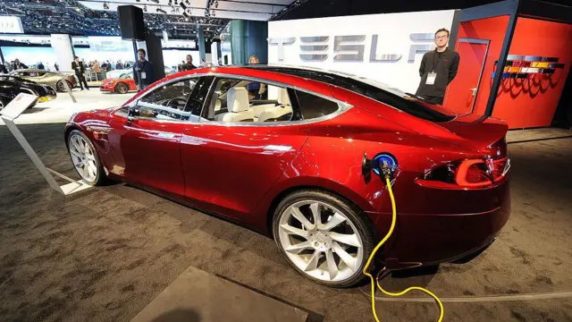 Un Model S de Tesla de color rojo está siendo recargado con electricidad.
