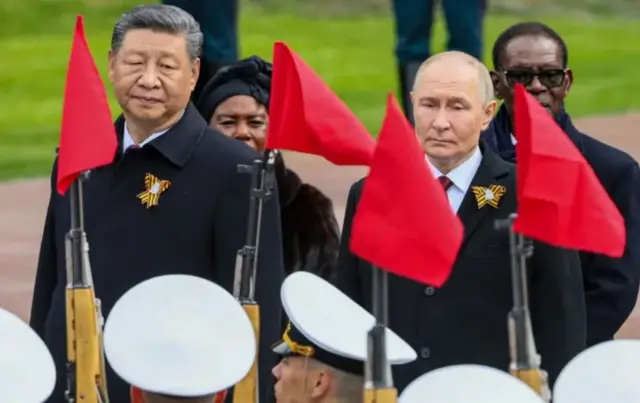 Путін був пліч-о-пліч із Сі Цзіньпінем. Обидва у чорних плащах. Вони дивляться на солдат з рушницями 