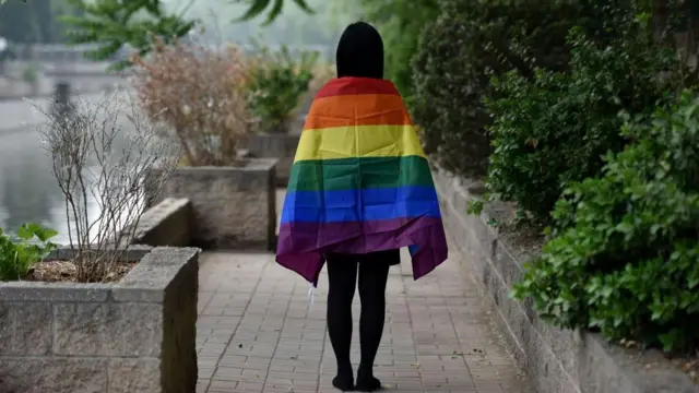 一位女士身披彩虹旗