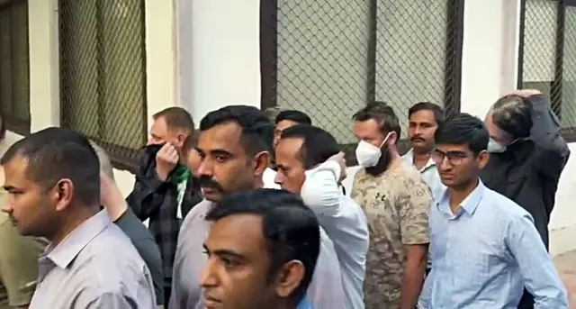 एनआईए के अधिकारी यूक्रेनी नागरिकों को अदालत में ले जाते हुए 