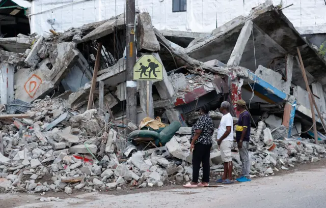 Varias personas observan un edificio destruido por el terremoto en Quibdó, Colombia, el 12 de agosto de 2026.