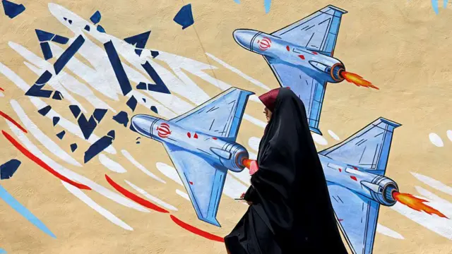 Tahran’da İsrail karşıtı bir duvar resminin önünden siyah çarşaf giymiş bir kadın geçerken, duvar resminde droneların Davut Yıldızı’nı parçaladığı görülüyor.