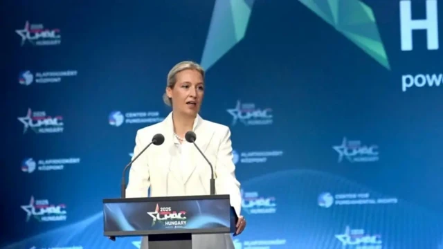 آلیس وایدل پشت میکروفون در حال سخنرانی