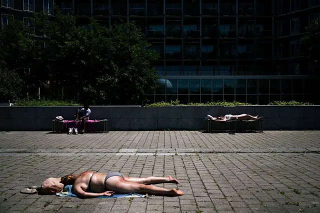 Gente tomando sol en el parque público André-Citroën en París el 29 de junio de 2025 mientras una ola de calor azota Europa.