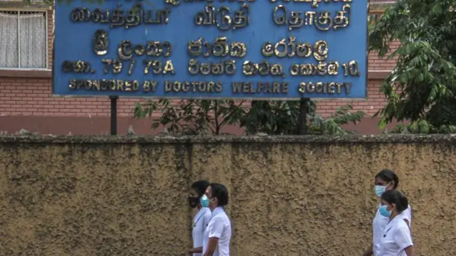 කොළඹ ජාතික රෝහල ඉදිරිපිට සෞඛ්‍ය සේවකයින් කිහිප දෙනෙක් ගමන් කරන අයුරු