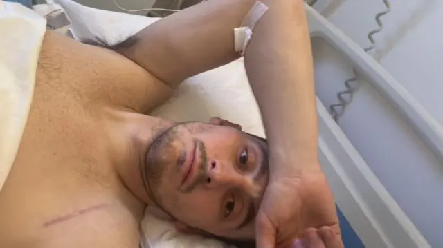 Sam Davies lying in a hospital bed