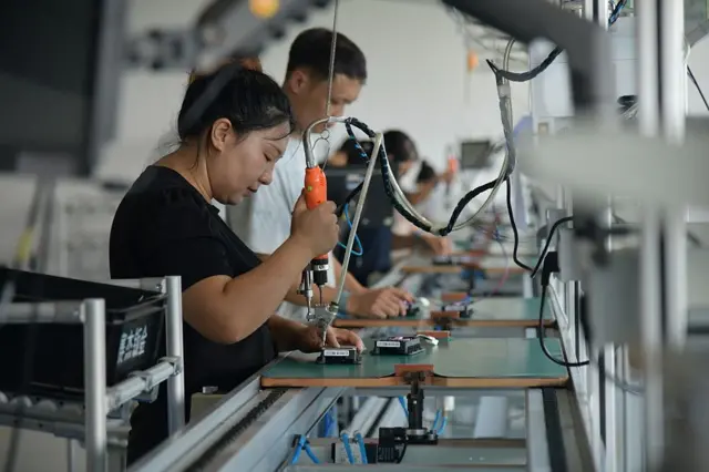 Des ouvriers assemblent le contrôleur MPPT, l'équipement de base du système d'extension de portée photovoltaïque monté sur véhicule, chez Geeco Solar Co., Ltd. le 29 juillet 2026 à Huzhou, province du Zhejiang en Chine.
