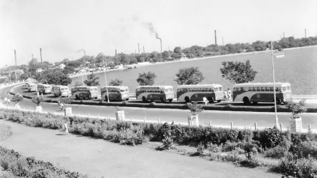 અમદાવાદના કાકરિયા તળાવનું દૃશ્ય જેમાં પાછળ મિલોનાં ભૂંગળાં નજરે પડે છે