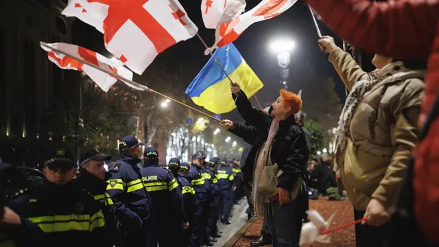 Протестующие с грузинскими и украинскими флагами перед строем полицейских
