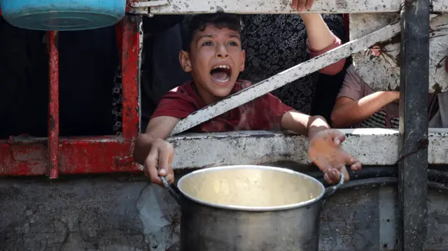 صورة تظهر فتى فلسطينياً ينتظر الحصول على طعام أمام أحد المطابخ الخيرية في مدينة غزة.