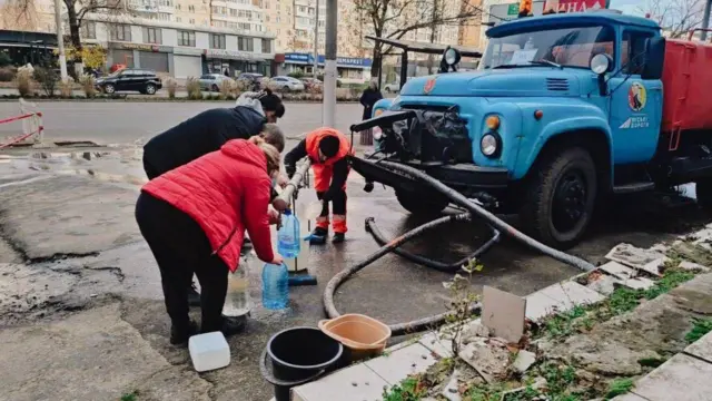 Люди набирают воду в канистры и ведра из цистерны