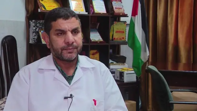Dr Marwan al-Hams wearing a medical coat and sitting down in his office at his hospital in Rafah