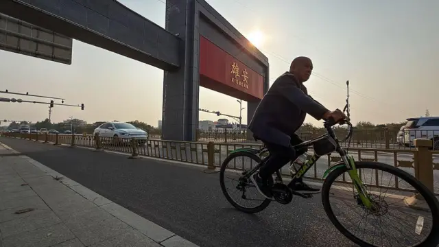 一個男子騎車經過雄安大門