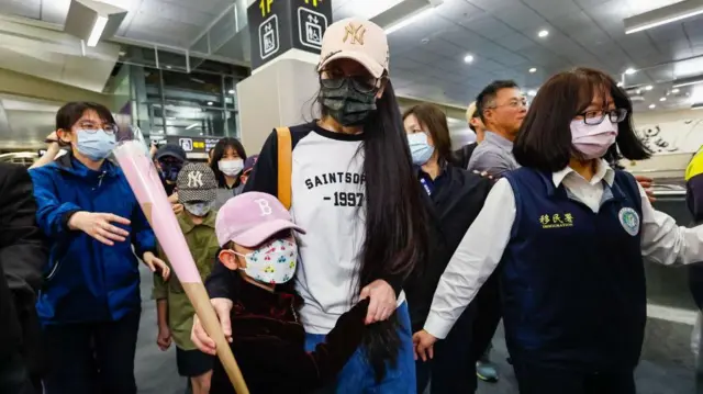 Chinese influencer 'YAYA' (Liu Zhenya) with a white and her daughter are escorted by police and immigration officers, as Yaya complies with Taiwan's legal order to leave Taiwan after her residency was revoked for posting videos advocating 'One China' and 'Unification with China by force', at Songshan Airport in Taipei, Taiwan, on March 25, 2025.