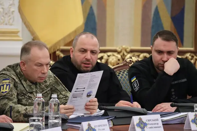 сырский слева рассматривает бумагу 