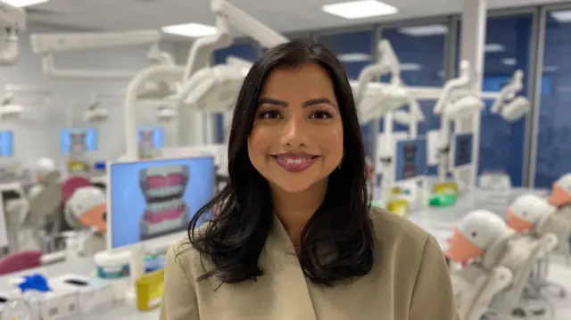 La Dra. Amrit Chauhan en un espacio de estudio de la Facultad de Odontología de la Universidad de Leeds. Sonríe a la cámara.