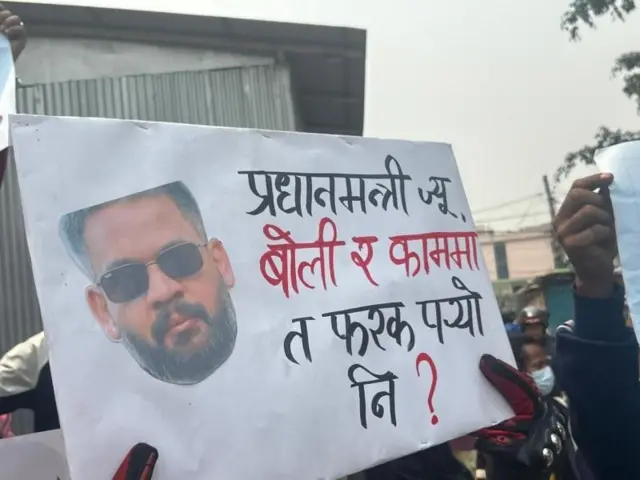 सुकुम्बासी बस्तीबाट विस्थापित मानिसहरूले प्रधानमन्त्री बालेनको तस्बिर अङ्कित प्लाकार्डमा उनलाई प्रश्न सोधेका छन् 