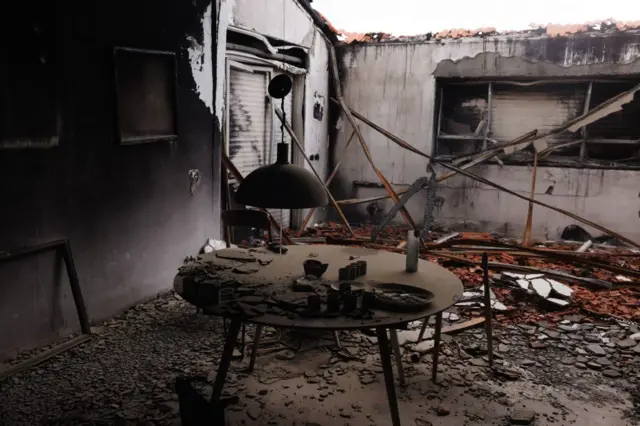 Un poêle, des murs effondrés et des morceaux de décombres sont visibles dans une pièce noire et incendiée d'une maison du kibboutz Be'eri, dans le sud d'Israël.