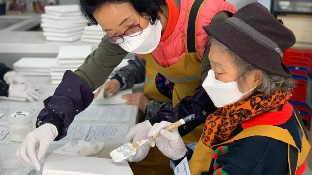 시니어 직원이 폐지로 캔버스를 만들고 있다