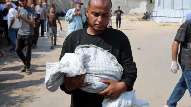 أحمد أبو حليب، والد الطفلة الفلسطينية زينب أبو حليب، التي توفيت بسبب سوء التغذية، وفقًا لمسؤولي الصحة، يحمل جثمانها، في خان يونس، جنوب قطاع غزة، 26 يوليو/تموز 2025. 