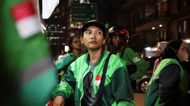 緑色のジャケットを着たバイクタクシーの運転手たちが、路上に停車している