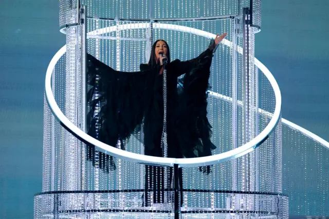 жена пева на сцени у црном костиму 