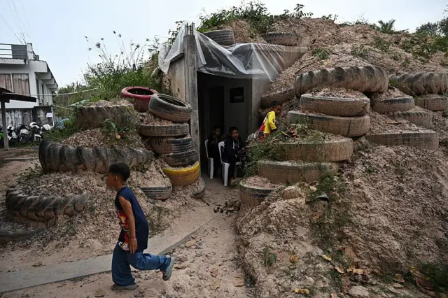  Children play around a bunker in Surin province on December 10, 2025, during clashes along the Thai-Cambodia border. Half a million evacuees in Cambodia and Thailand were sheltering in pagodas, schools and other safe havens on December 10 after fleeing renewed fighting in a century-old border dispute in which US President Donald Trump has vowed to again intercede. (Photo by Lillian SUWANRUMPHA / AFP via Getty Images)