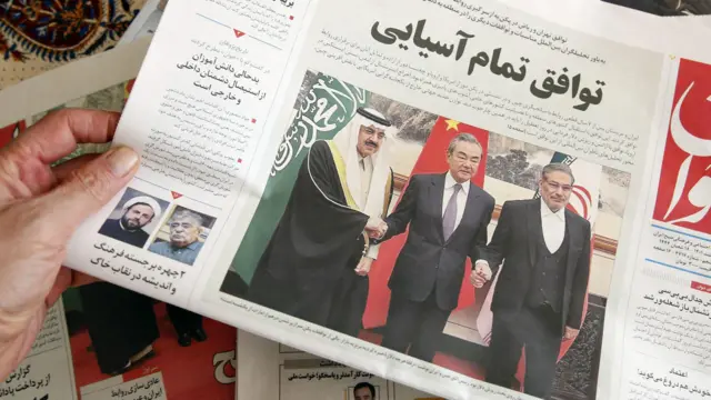 رجل في طهران يحمل صحيفة محلية تنشر على صفحتها الأولى تقريرا عن الاتفاق الذي توسطت فيه الصين بين إيران والمملكة العربية السعودية لاستعادة العلاقات، والذي تم توقيعه في بكين في اليوم السابق، 11 مارس/آذار 2023.