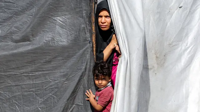 Una mujer y un niño miram desde una tienda de campaña en Gaza.