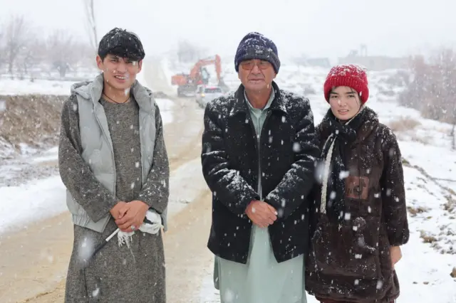 تصویر دو مرد و یک دختر در زیر برفباری 