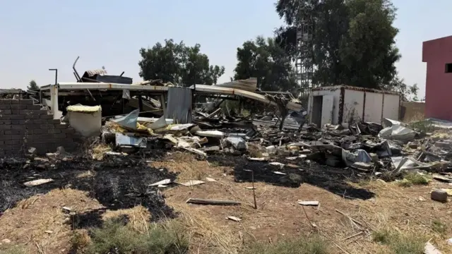 حطام متناثر على الأرض، وتظهر أشجار خلف الدمار