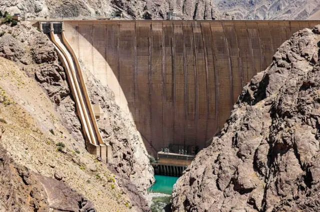 Entre las rocas se puede ver un embalse con bajo nivel de agua, con el muro de la presa Amir Kabir elevándose sobre la extensión de agua.