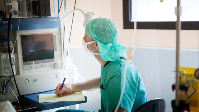 Dokter anestesi mencatat tanda-tanda vital pasien.