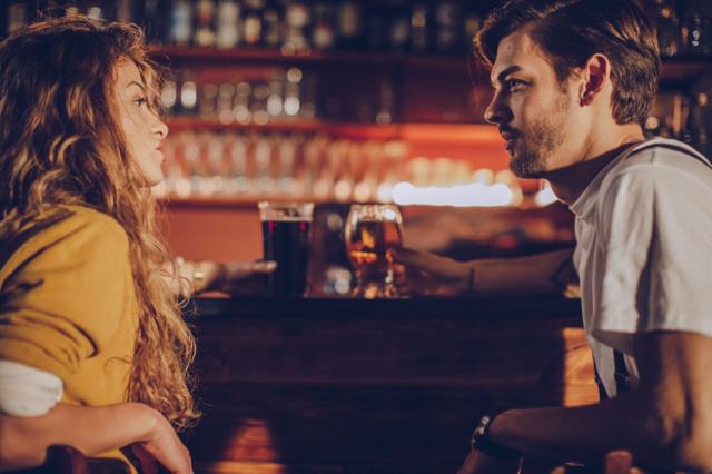 Homem e mulher se olhando sentados em balcão de bar 