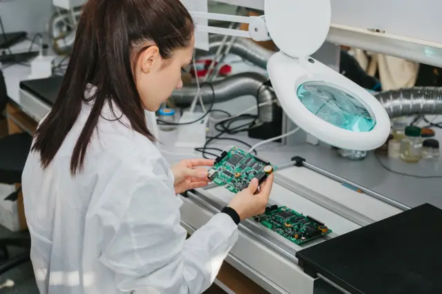 Trabalhadora com placa com semicondutores nas mãos